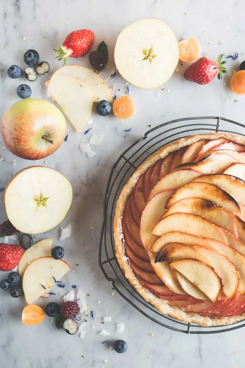 Appeltaart tussen verse appels en rood fruit