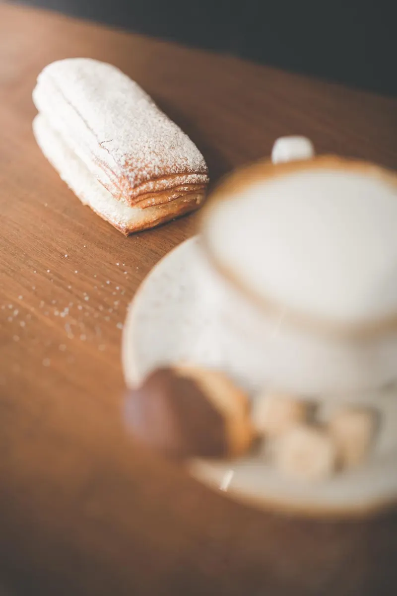 Bladerdeeggebakje naast een kop koffie